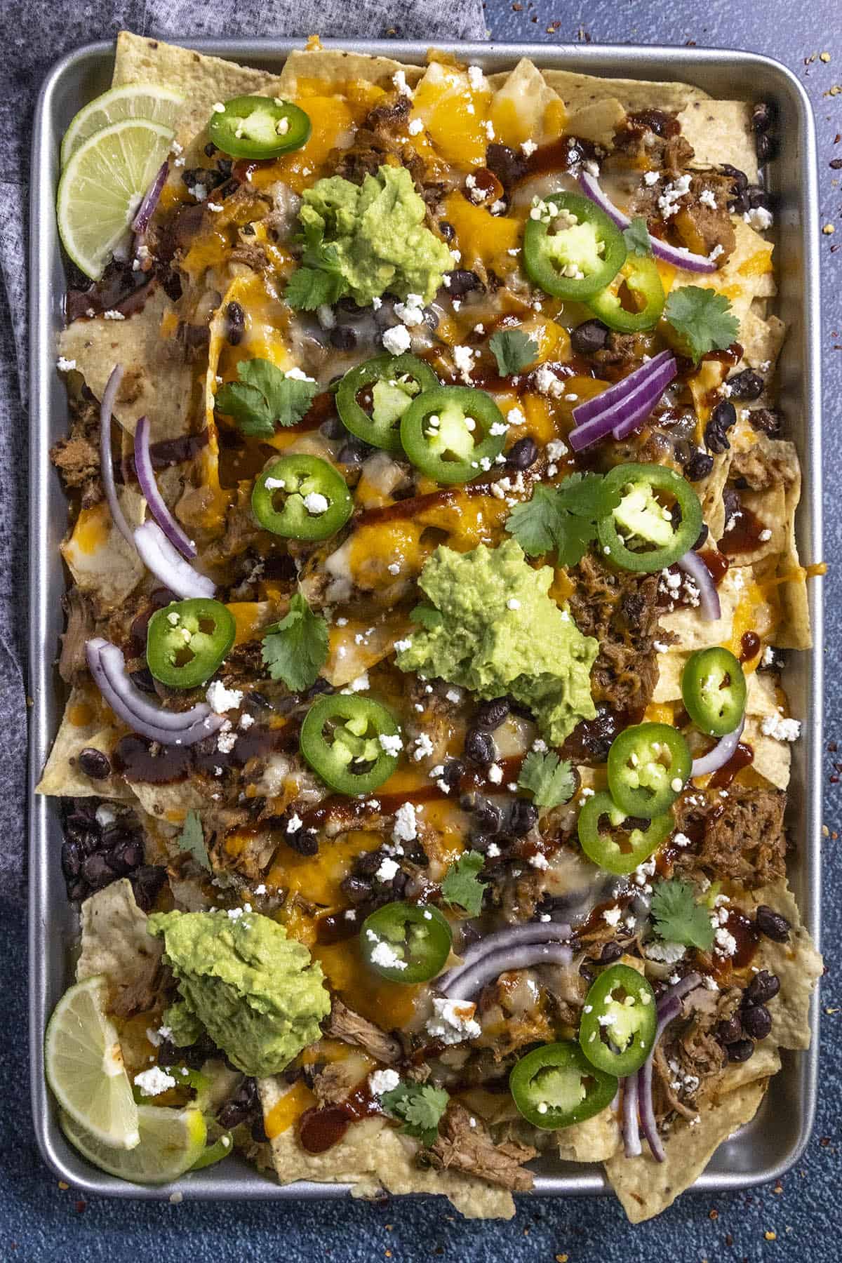 Pulled Pork Nachos served on a baking sheet with lots of toppings