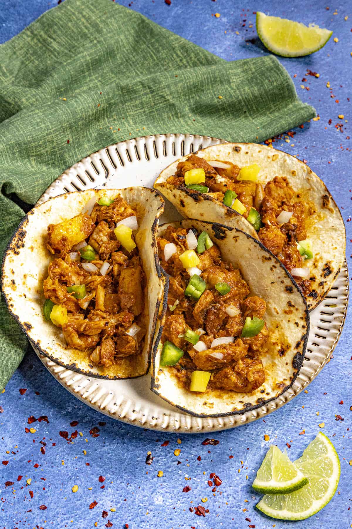 3 Chicken al Pastor tacos on a plate garnished with chopped onion, jalapeno, and fresh pineapple.