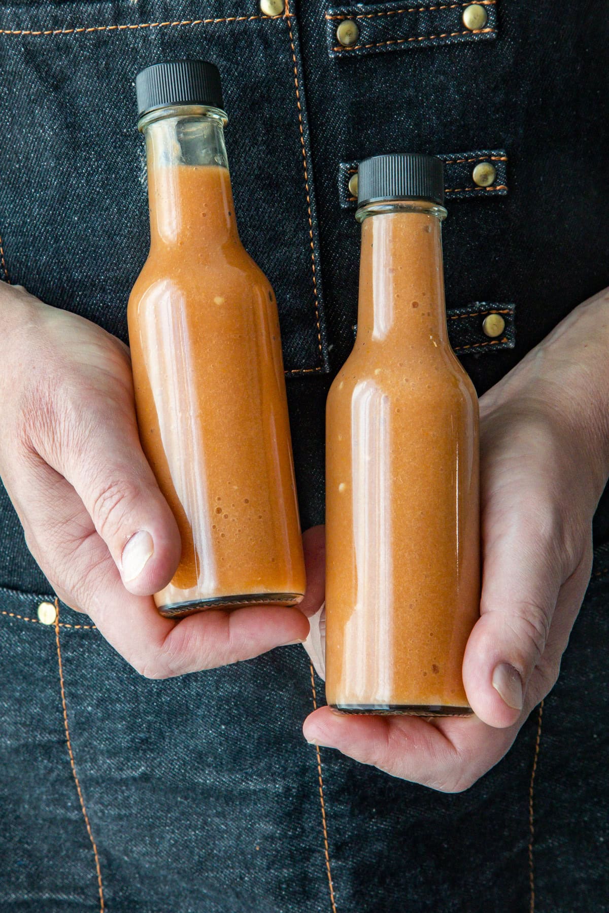 Mike holding two bottles of sweet and spicy Mango-Habanero hot sauce