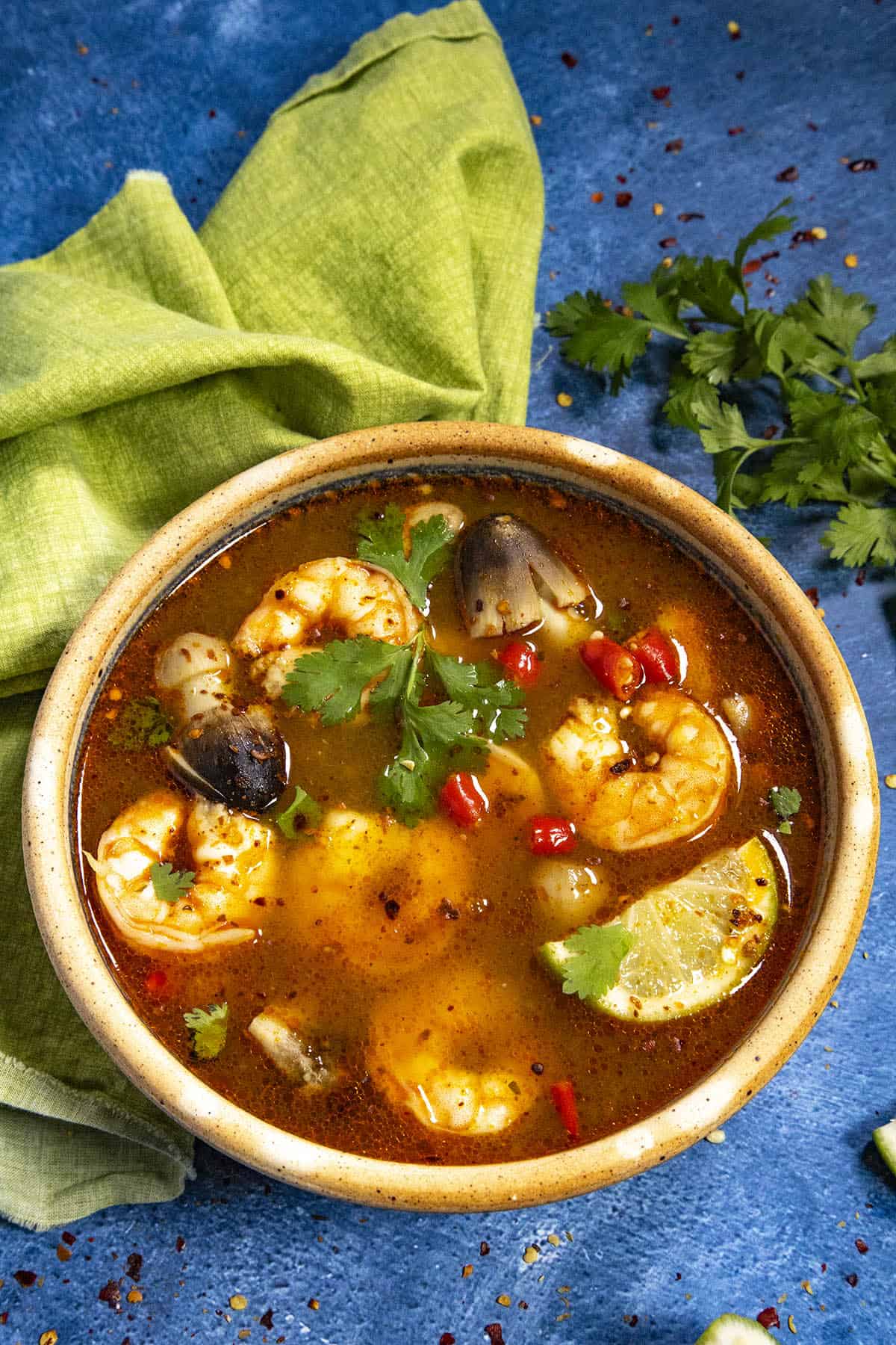 A bowl of Tom Yum Soup with lots of shrimp and mushrooms, ready to serve