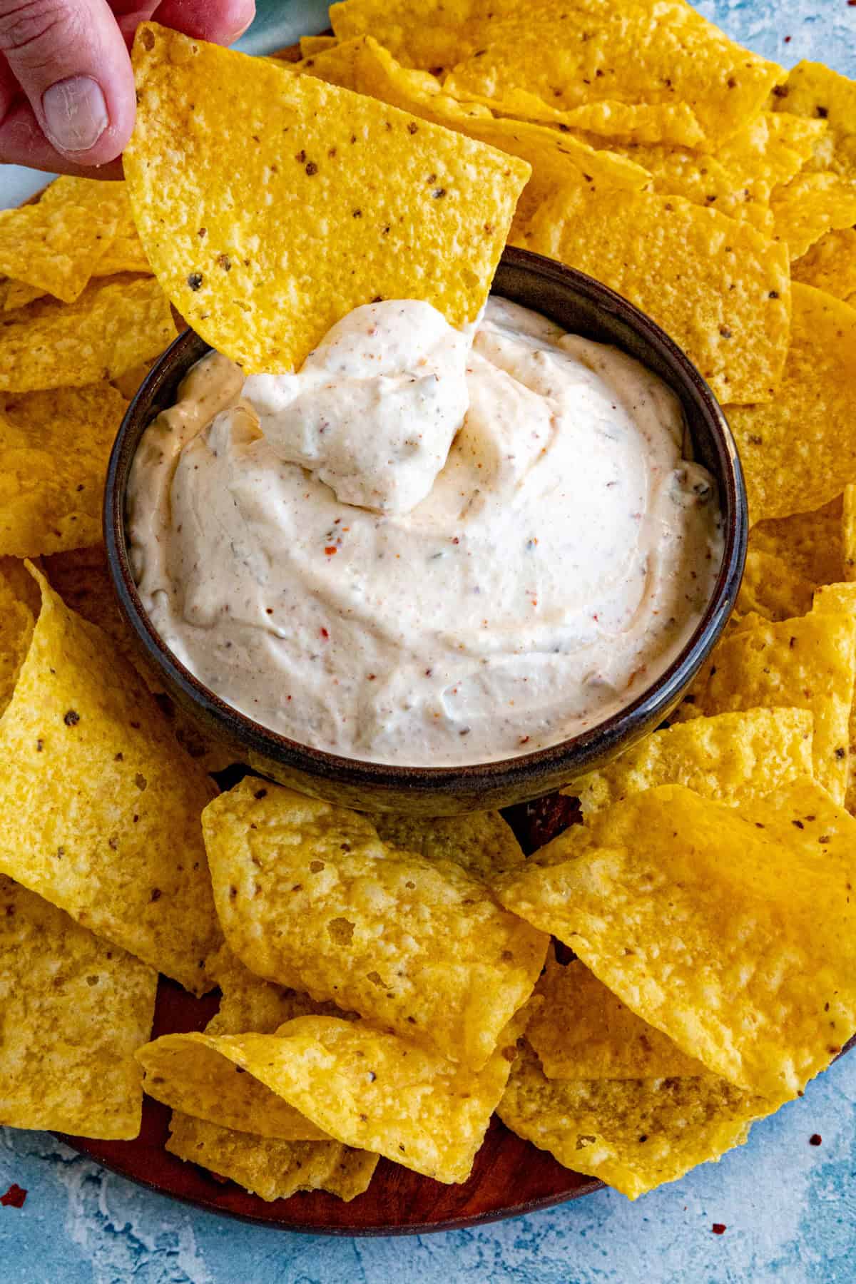 Dipping a crispy tortilla chip into a bowl of Mexican White Sauce (Salsa Blanca)
