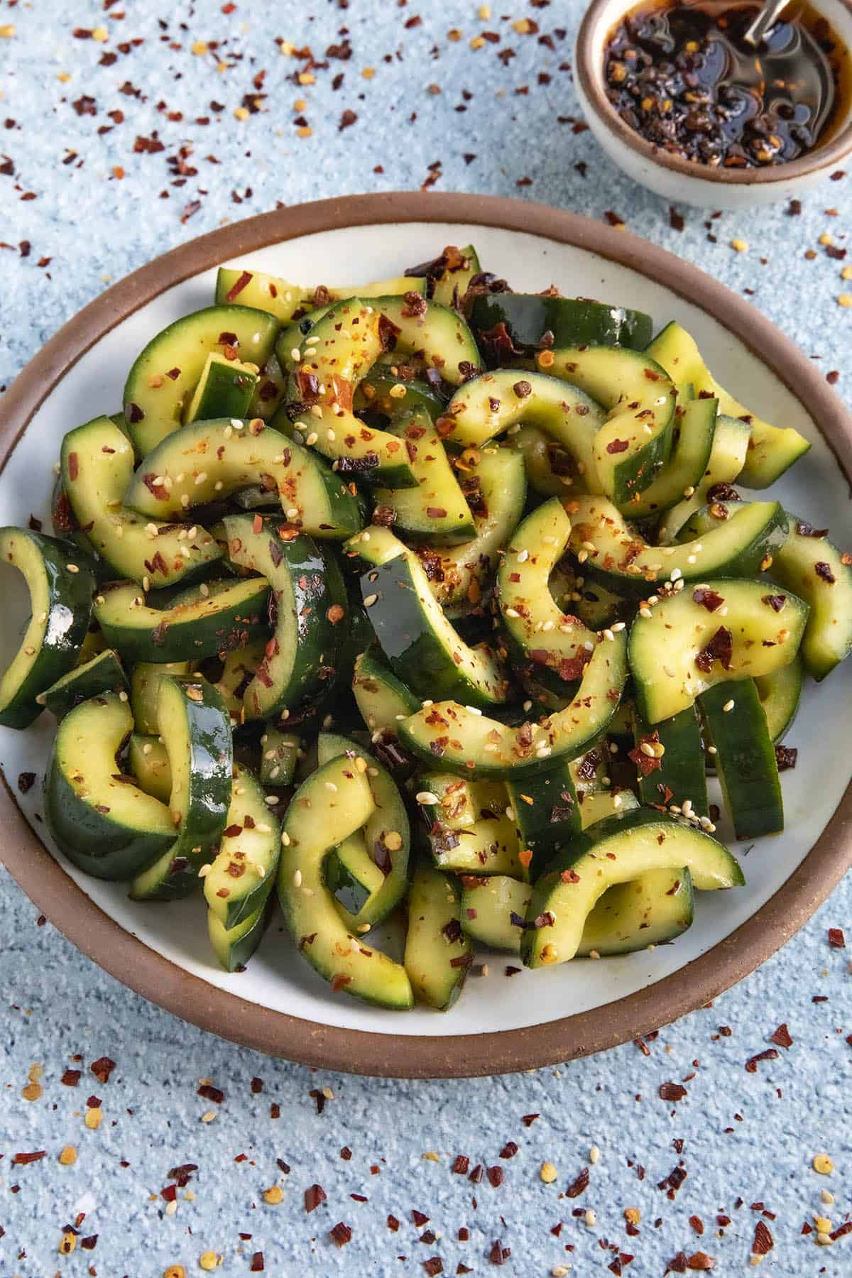 Sichuanese Spiced Cucumber Salad (Qiang Huang Gua) in a serving bowl with extra dressing on the side