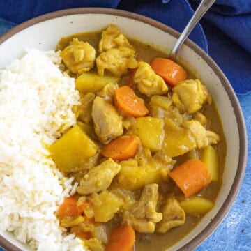 A bowl filled with hearty Japanese style curry with lots of potatoes and carrots, served with rice