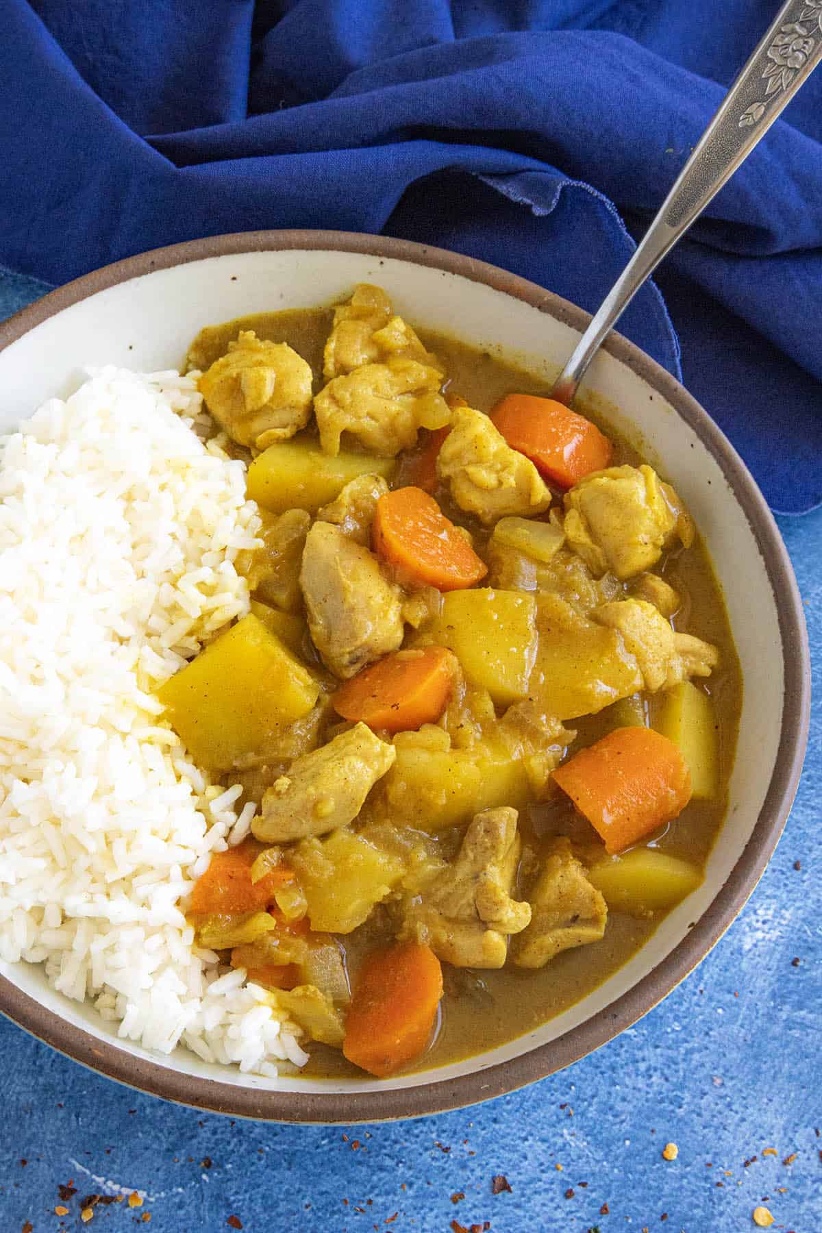 A bowl filled with hearty Japanese style curry with lots of potatoes and carrots, served with rice