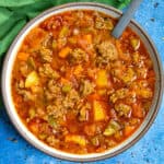 A bowl of chunky hamburger soup with a spoon