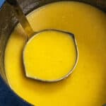 Creamy roasted garlic gravy being served from the pot with a ladle