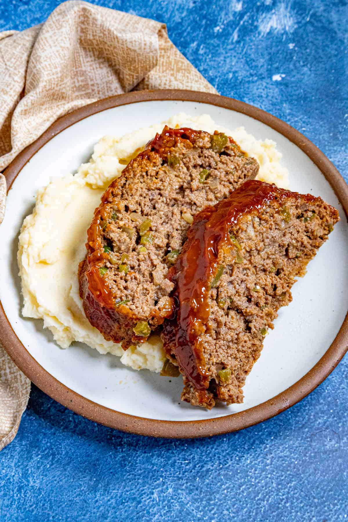 Thick slices of southern style meatloaf served over mashed potatoes on a plate