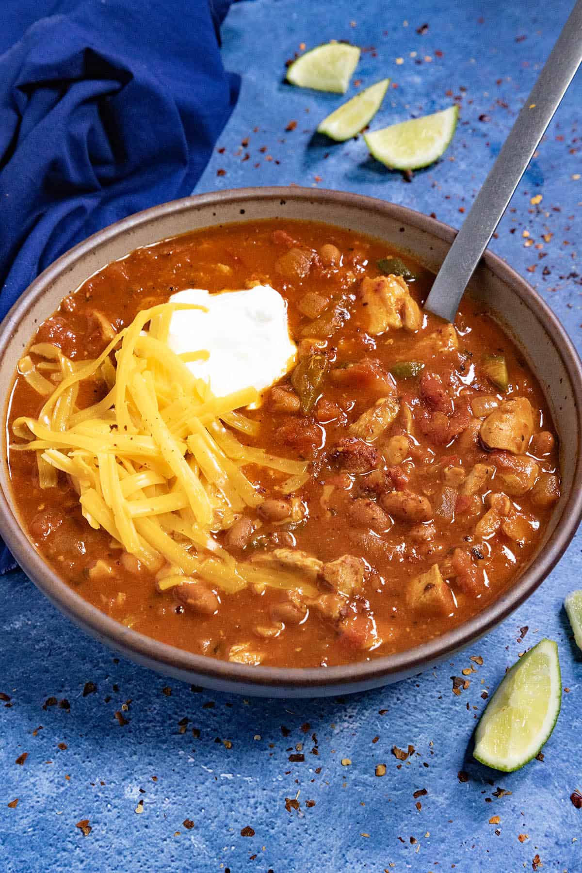 Homemade Chicken Chili in a bowl, topped with shredded cheddar cheese and sour cream