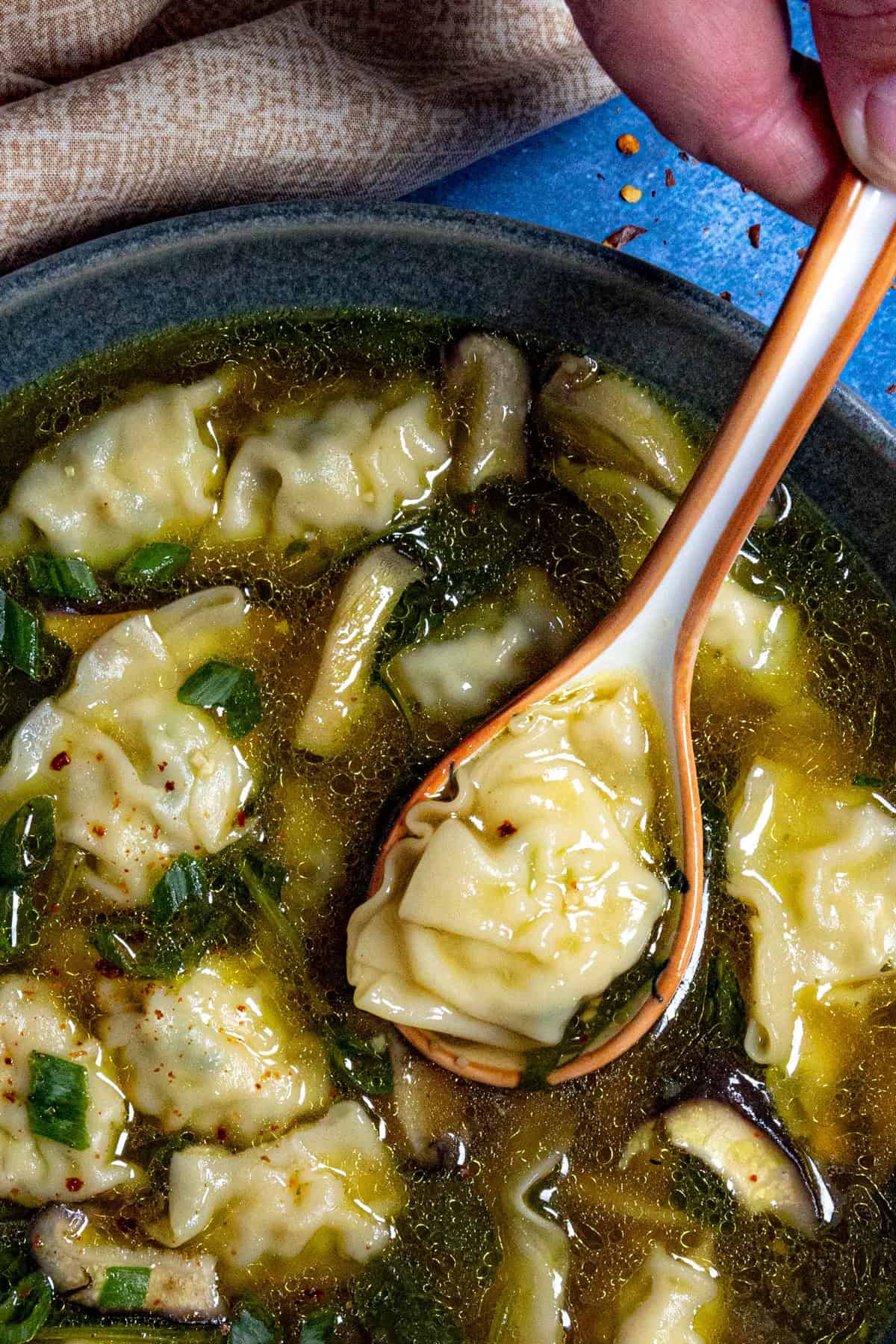 Mike taking a scoop of wonton soup from the bowl with a soup spoon